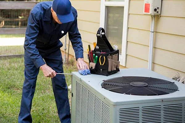 HVAC technician performing maintenance on an outdoor residential system