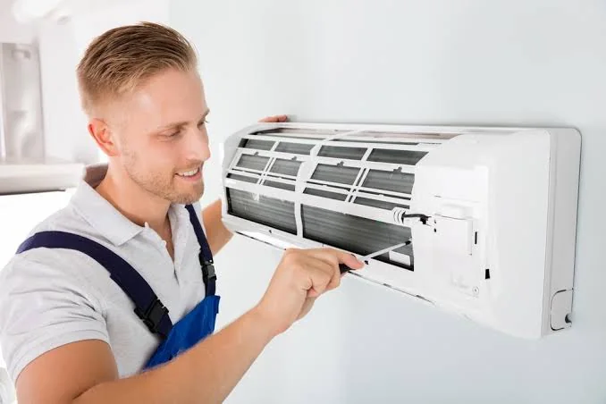 Technician inspecting a wall-mounted air conditioning unit