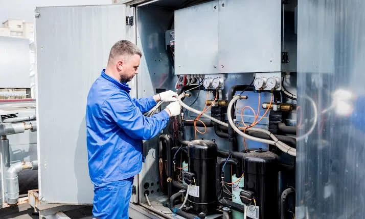 Technician inspecting internal components of commercial heating equipment