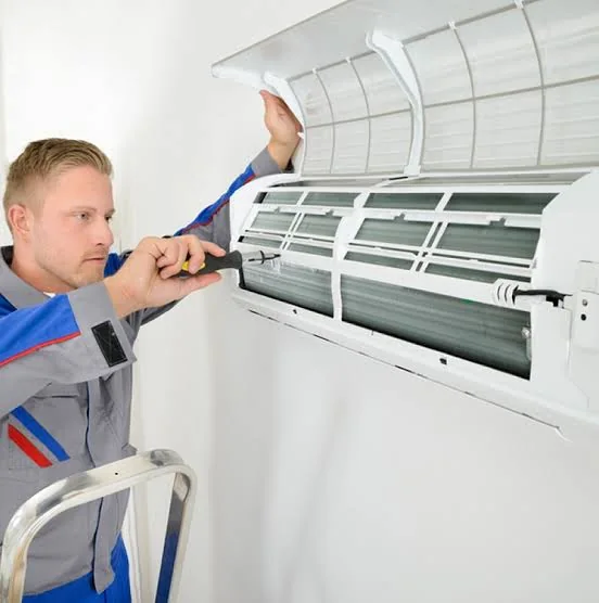 Technician servicing a residential wall-mounted heating and cooling unit